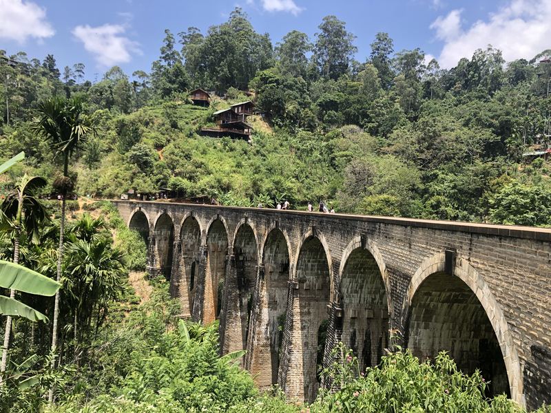 Steinerne Eisenbahnbrücke mit neun Bögen, mitten im grünen Bergwald