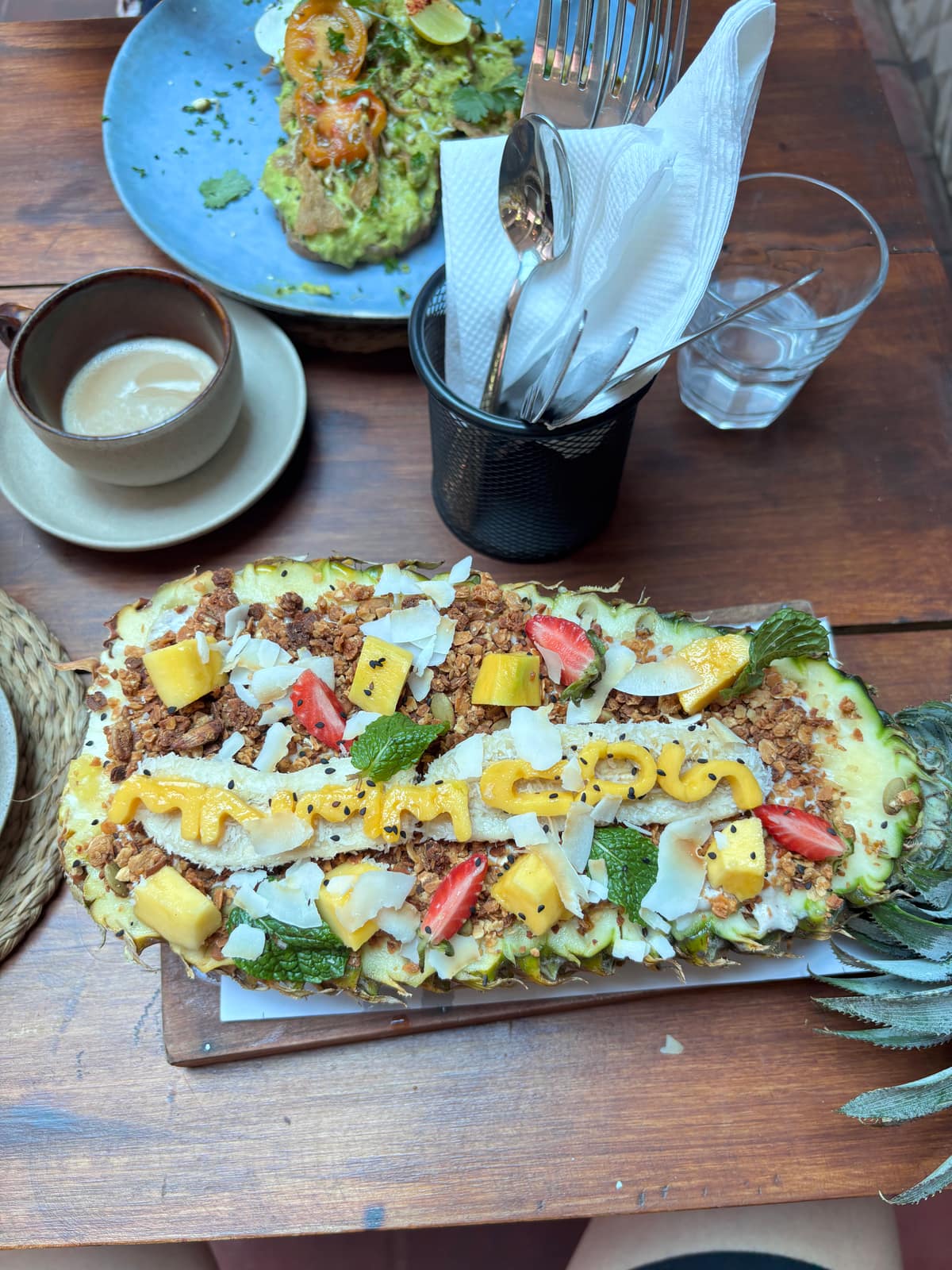 Frühstücks-Bowl in einer ausgehöhlten Ananas: Granola, Mango, Kokos-Chips und Minze